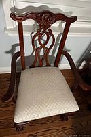 Front view of arm dining chair showing carved back, arms, upholstery