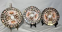 Front view of three Royal Crown Derby Imari plates on stands