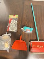 Overview showing sweeper, iron, dustpan, sealed salad set, bagged bakeware