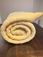 Rolled yellow foam mattress pad on wooden surface