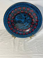 Front view of painted clay plate on metal stand