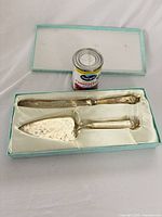 Cake knife and pie server in satin-lined box with can for scale