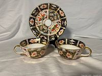 Front view of two Imari teacups and saucer showing design