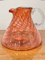 Close-up of ruby red ribbon swirl art glass pitcher with clear handle