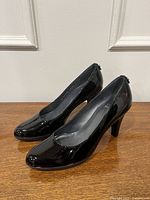 Side view of both pumps showing patent leather shine and heel profile