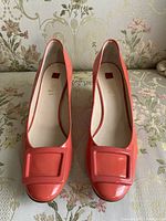 Top view of coral patent leather pumps showing square buckle and squared toe