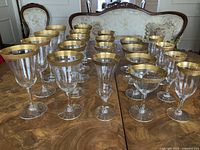 All 21 gold-rimmed glasses arranged on table, showing two sizes