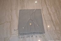 Wrap folded to show full width, fringe, decorative stitching and discs