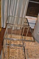Two chrome frame glass side tables nested together