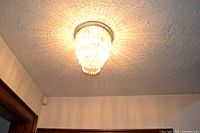 Illuminated ceiling-mounted tiered crystal chandelier