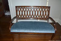 Front view of carved wood bench with blue upholstered seat