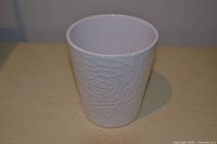 Front view of white ceramic vase with embossed floral pattern