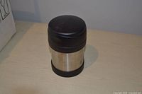 Thermos exterior view showing stainless steel body and black plastic lid/base