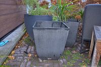 Two black square tapered Veradek planters outdoors on patio