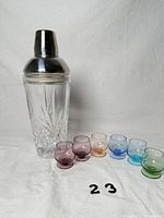 Cocktail shaker front view with six colored shot glasses