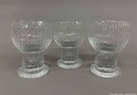 Three clear textured glass goblets front view