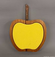 Front view of apple-shaped cheese board showing yellow surface and wood frame