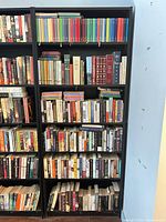 Full view of tall dark espresso bookcase with six shelves loaded with books