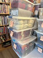 Stack of four clear bins filled with yarn skeins in assorted colors