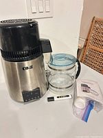 Distiller main unit with glass carafe, TDS meter, accessories bag visible