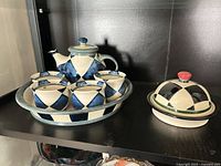 Full set on shelf: teapot, four cups on tray, covered dish