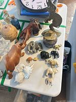 Overall view of lot on table showing mix of elephant figurines and wooden rhinoceros