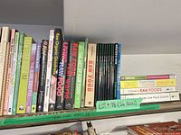 First shelf showing multiple raw food cookbooks including Raw Food Real World, Living Raw Food, Raw Organic Goodness, The Art of Raw Food, Rawvolution and others