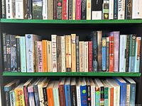Full view of three shelves; top labelled 29 books; shows variety of mixed paperback fiction titles