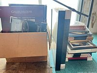 Cardboard box and stacked assortment of picture frames, some sealed in packaging showing Gallery Solutions branding