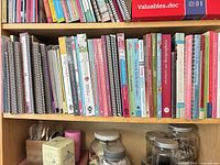 Shelf with two rows of assorted scrapbooking books and spiral journals
