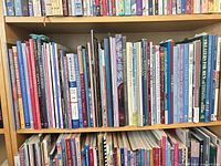 Full view of two shelves filled with knitting and needlework books and magazines