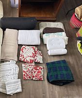 All items laid out on floor showing variety: blankets, sheet set, duvet set, bath mats, bolster, support pillow