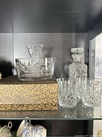 Decanter, three glasses and round cut crystal bowl displayed on shelf
