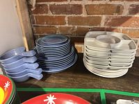 stacked blue plates, blue handled bowls, white divided trays