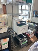 Full view of chrome wire shelving rack holding various office equipment