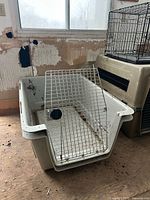 Angled view of plastic crate base with detached metal wire door leaning inside