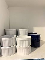 Stacks of white and blue ribbed ceramic ramekins on shelf