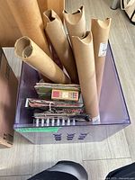 Purple plastic tote holding six kraft-wrapped vinyl rolls and several mini albums