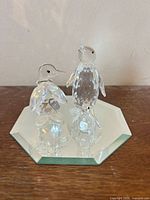 Two crystal penguin figurines on octagonal mirror base