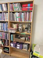 Full view of bookcase filled with books and supplies, shows six shelves and overall design