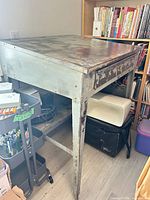 Perspective view showing slanted steel table with drawer and shelf