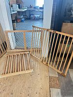 Three wooden gate panels including one with mesh insert placed on floor