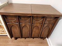 Front view of walnut-tone sewing cabinet showing sculpted Brasilia style panels