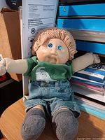 Front view of Cabbage Patch Kids doll seated, showing face, shirt, shorts, socks
