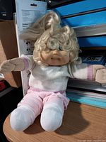 Full view of doll seated showing clothing and hair