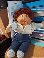 Front view of doll seated showing outfit and face