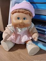 Front view of Cabbage Patch Kids doll seated on desk