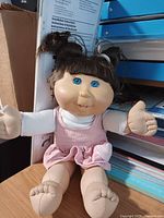 Full view of doll seated showing hair, eyes, clothing, and limbs