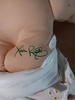 Close-up of green Xavier Roberts signature on doll's fabric body