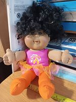 Full view of 13-inch Cabbage Patch Kids cheerleader doll seated against books for scale, measuring tape visible